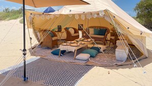 A tent with a dining area, including wicker furniture and a table set for four. - Yurt on the Beach (Bolivar Peninsula)