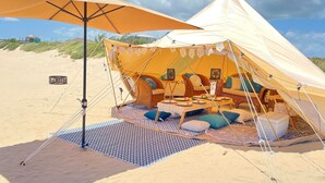 A tented accommodation with a dining area, seating, and a view of the beach. - Yurt on the Beach (Bolivar Peninsula)