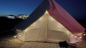 A pyramid-shaped tent with string lights and a patterned mat on the ground. - Yurt on the Beach (Bolivar Peninsula)