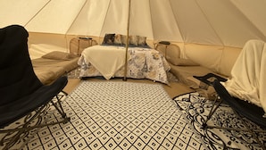 A tent with a bed, two chairs, a table, and a patterned rug. - Yurt on the Beach (Bolivar Peninsula)