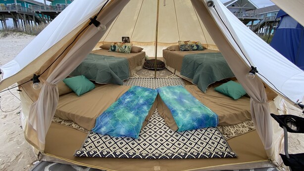 A tent with two beds, each with a patterned bedspread and pillows. - Yurt on the Beach (Bolivar Peninsula)