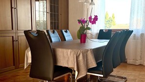 Ein Essbereich mit Tisch, Stühlen und einem Fenster mit Vorhängen.
