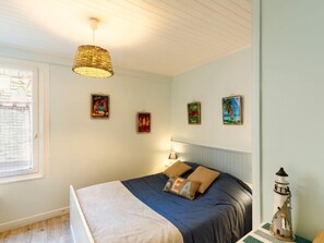 Een slaapkamer met een bed, een hanglamp en wanddecoratie.