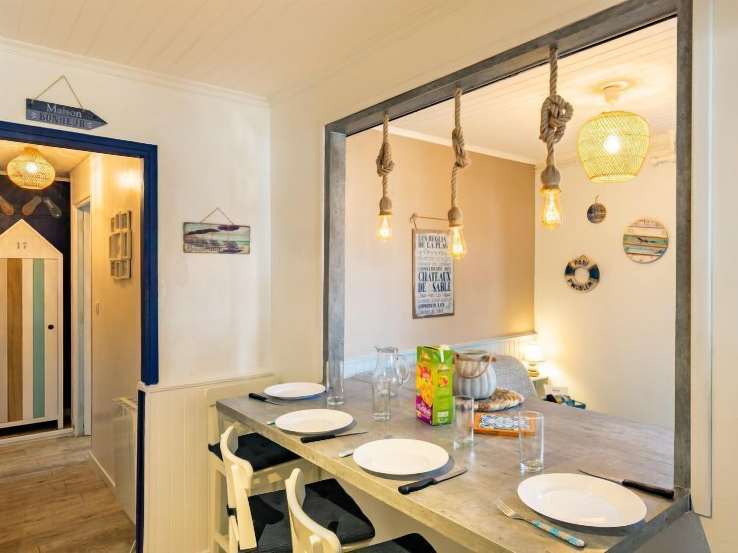 A dining area with a wooden table set for four, a large mirror above the table, and various decorative items on the walls.