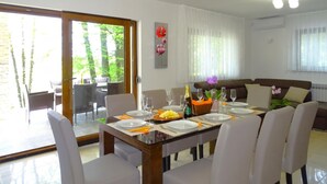 A dining area with a table set for six, chairs, a sofa, and a view of the outdoors.