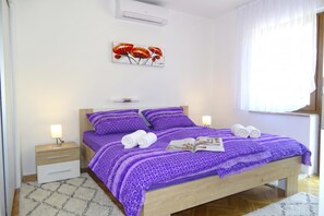 Une chambre à coucher avec un lit, des tables de chevet, une lampe, un tableau et une fenêtre avec des rideaux.