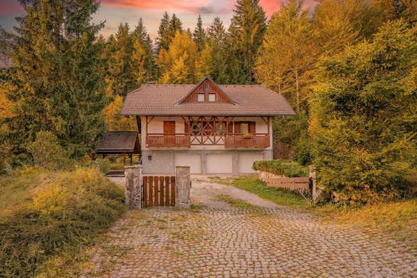 Eine Chalet mit Natursteinfundament, Holzbalkon und Kopfsteinpflasterzufahrt.