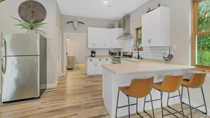 Een moderne keuken met een centraal eiland, witte kasten en een roestvrijstalen koelkast.