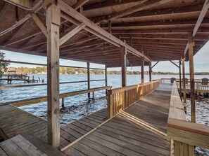 A wooden pier extending over water with a covered area and benches. - Talquin Time: Lakefront - Dock - Pool Table (Quincy)