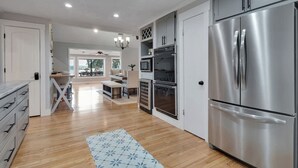 Une cuisine moderne dotée d’appareils électroménagers en acier inoxydable, d’un plancher en bois et donnant sur un coin repas.