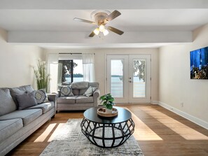 A living room with a grey sofa, a round coffee table, and a ceiling fan.