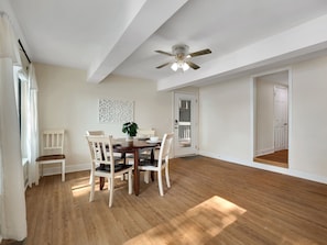 A dining area with a wooden table, white chairs, and a ceiling fan. - Talquin Time: Lakefront - Dock - Pool Table (Quincy)