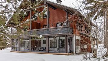 Et toetagers træhus med facade af glas og en balkon.