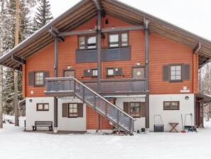 A multi-story chalet with a wooden exterior, a balcony on the second floor, and a staircase leading to the upper levels. - Alppitalo sinitähti 9 as 1 by Interhome (Nilsiä)