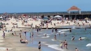 Une plage bondée où les gens se baignent et prennent des bains de soleil.