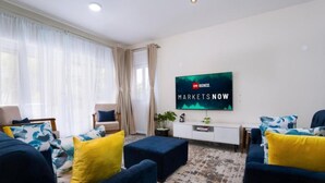 Un salon moderne avec un téléviseur fixé au mur, un ensemble de canapés et une table basse.