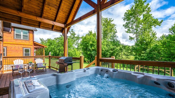 A wooden deck with a hot tub, outdoor furniture, and a view of a house in the background.