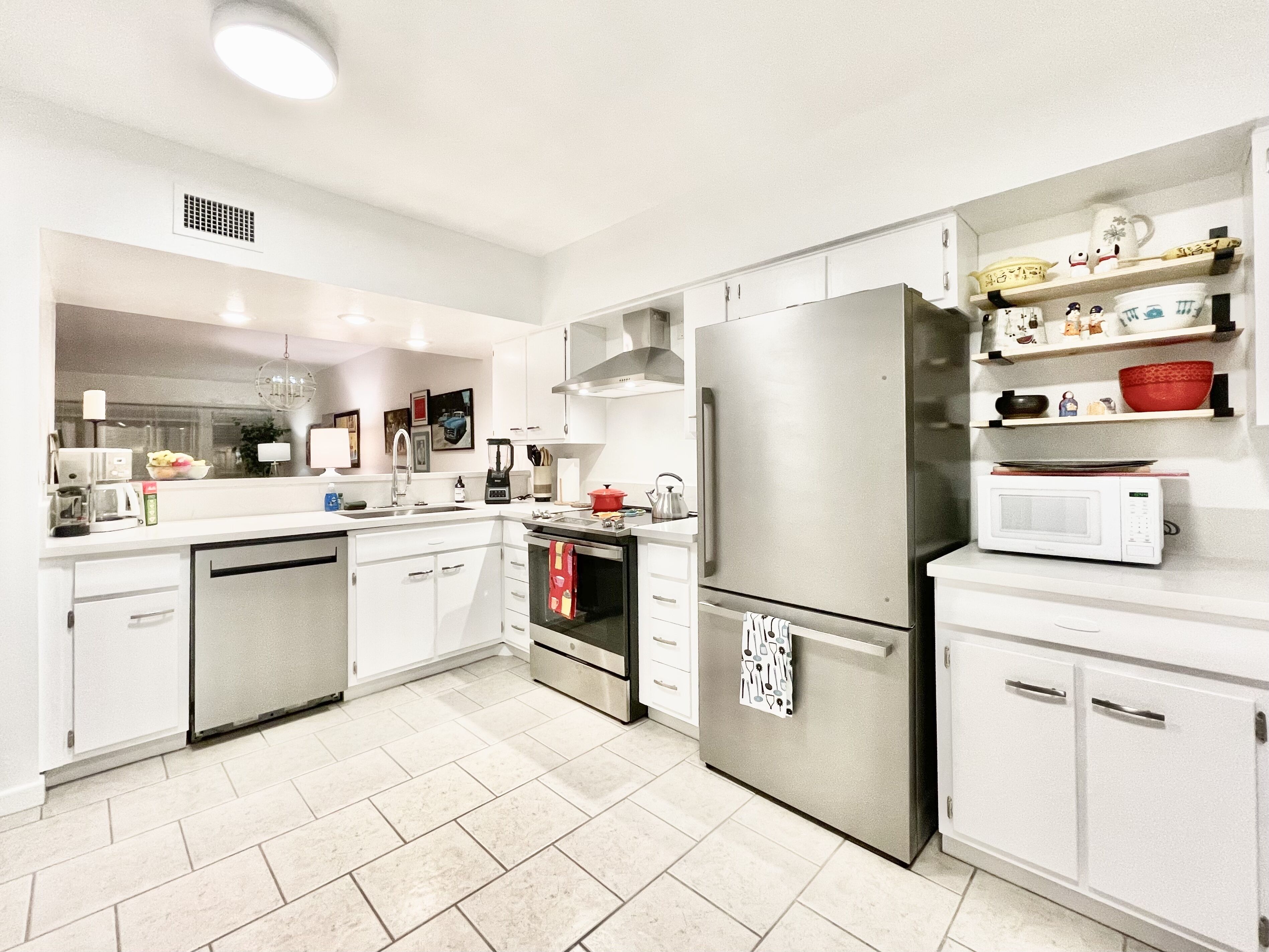 A modern kitchen with white cabinetry, stainless steel appliances, and a tiled floor.