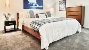 A bedroom with a bed, bedside tables, a dresser, a hanging light fixture, and a painting on the wall. - BIG DISCOUNTS ! Fabulous DOWNTOWN Palm Springs! Gorgeous Mid Century. BEST area! (Palm Springs)