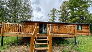 Une cabane en bois dotée d’une terrasse et d’un escalier menant à une porte.