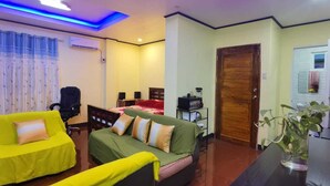 Um quarto com sofá, cama, escrivaninha e porta de madeira.