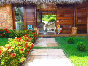 A thatched-roof building with a stone pathway leading to a seating area. - Pousada Villa Mariposa (Beberibe)