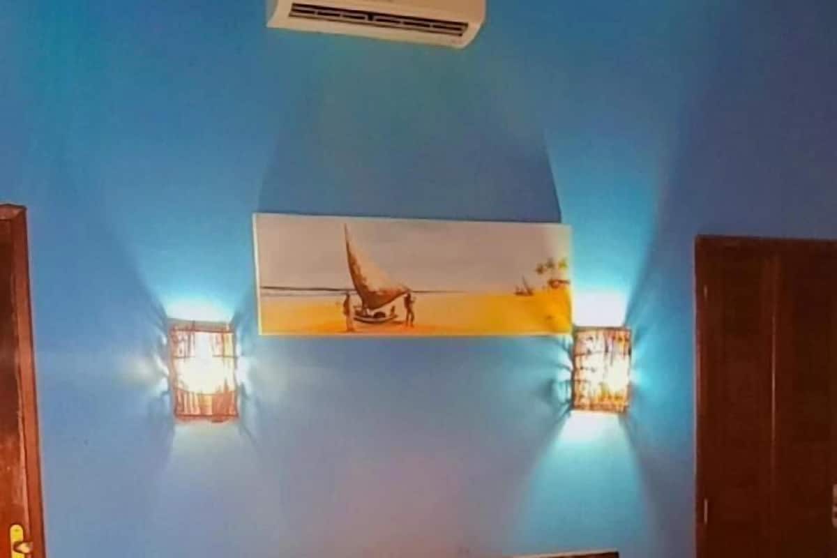 Een slaapkamer met een bed, nachtkastje, airconditioning en wandlampen.