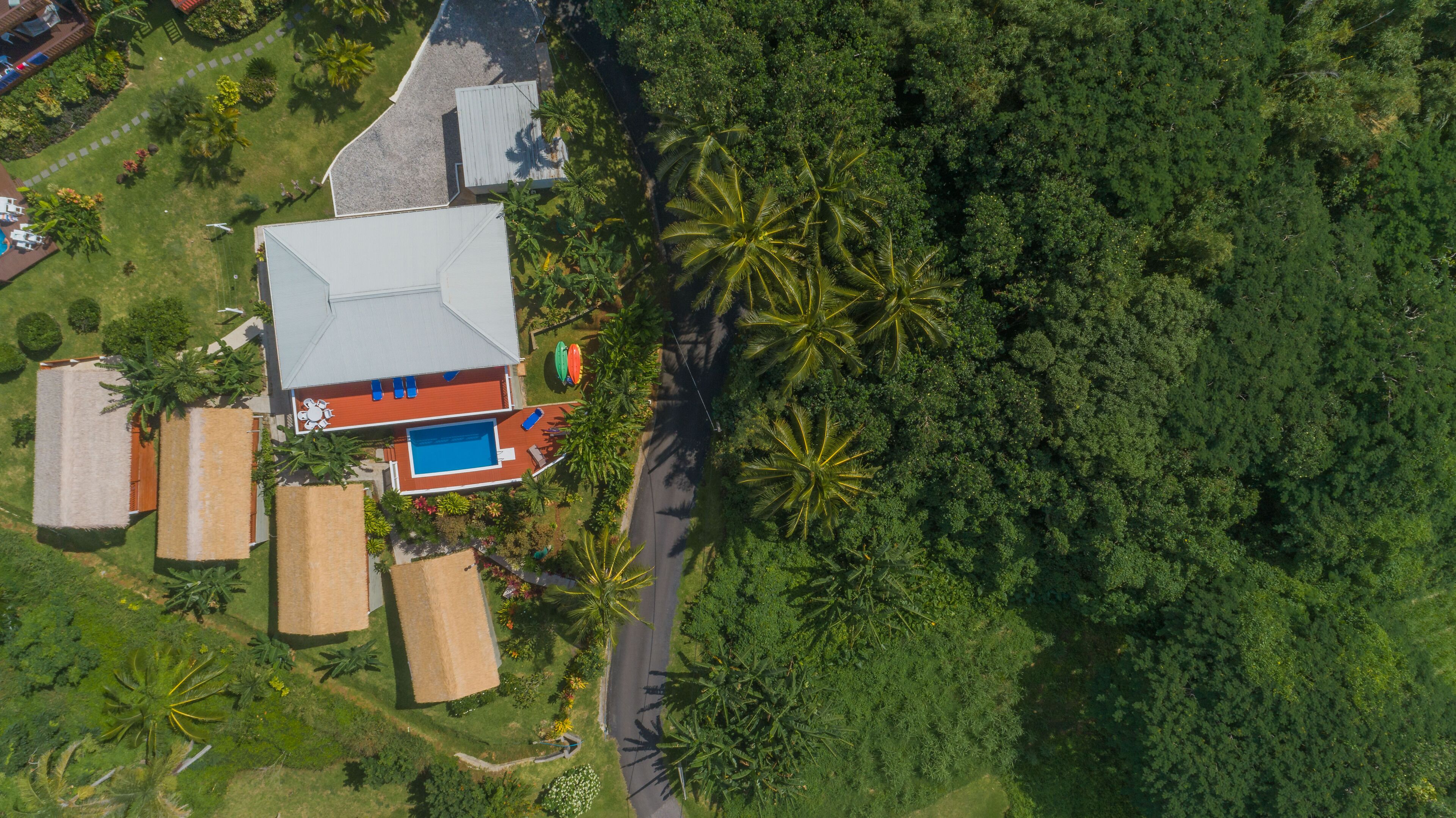 Vista aérea de uma propriedade com piscina, varanda coberta e acesso por estrada.