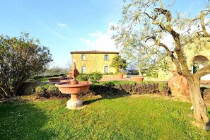 Un patio con una fuente, un edificio con techo de tejas y un árbol.