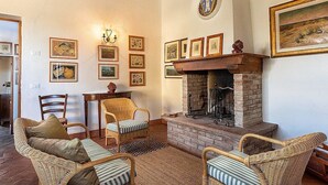 Ein gemütliches Wohnzimmer mit Korbmöbeln, einem Kamin und gerahmten Bildern an den Wänden.