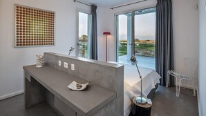 Een moderne hotelkamer met een groot bed, een bureau met lamp, uitzicht op de omgeving en een uniek kunstwerk aan de muur.