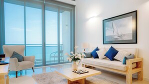 A modern living room with a sofa, armchair, coffee table, and a large window offering a view of the sea. - Oceanfront Galle by ICC (Galle)