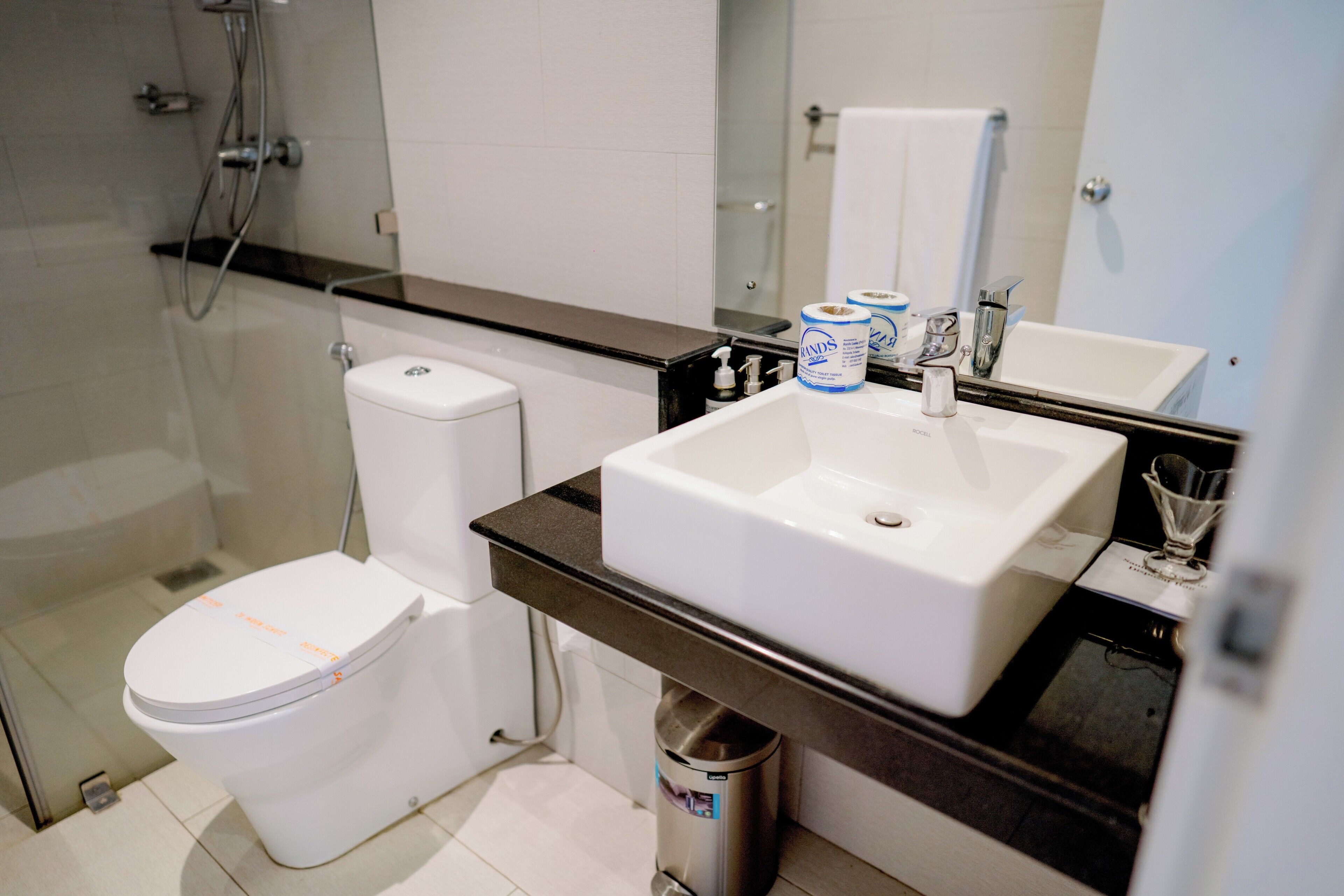 Un baño moderno con inodoro blanco, lavamanos y zona de ducha.