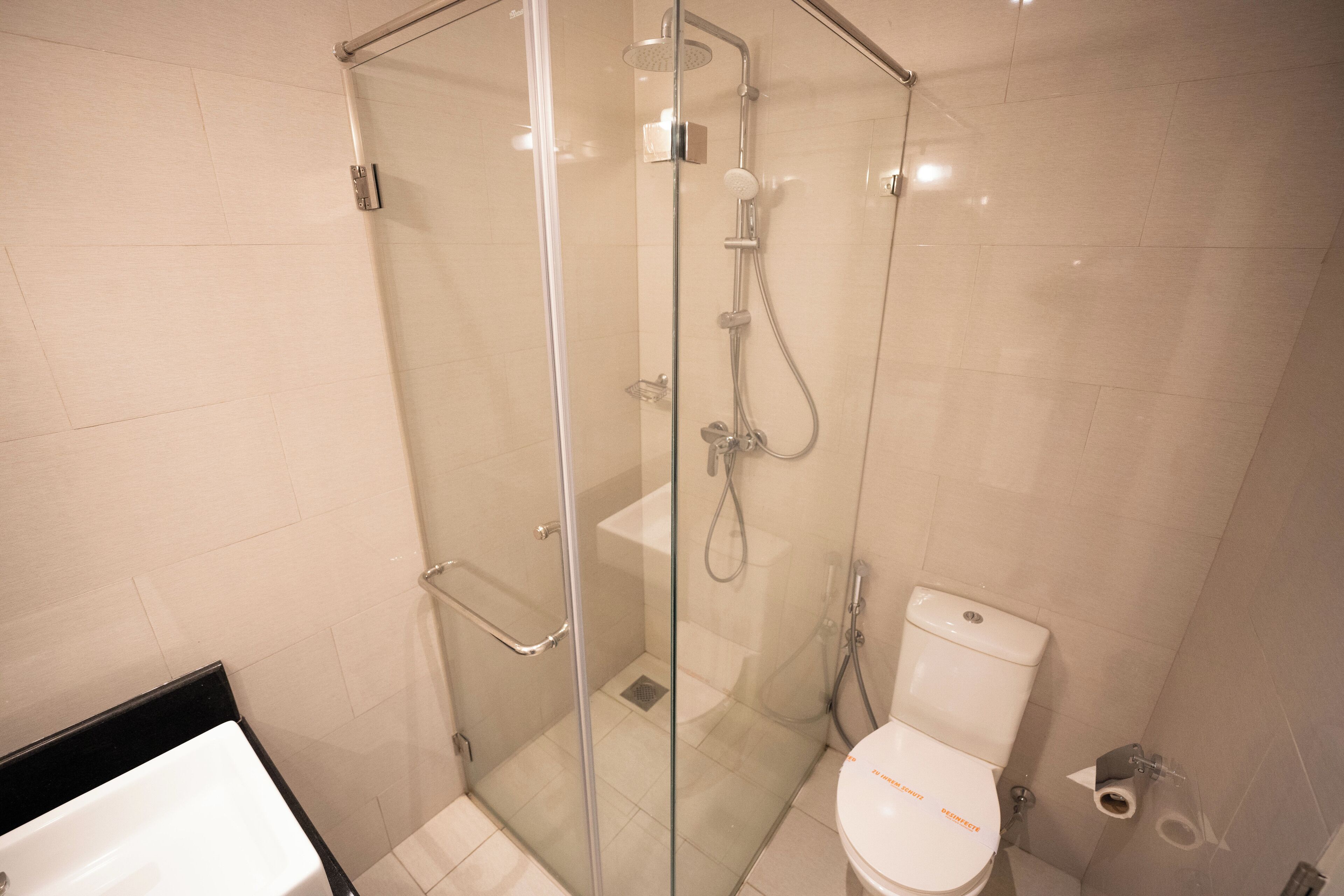 A modern bathroom with a glass-enclosed shower, a white toilet, and a bathtub.