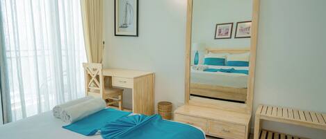 A bedroom with a bed, a desk, a mirror, and a small wooden bench.