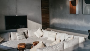 Una sala de estar moderna con un amplio sofá modular, un televisor de pantalla plana montado en la pared y obras de arte abstracto.