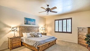 A bedroom with a wooden bed, two bedside tables, a ceiling fan, a window, and a dresser. - Deck & Game Room: Spacious Pinetop Cabin! (Pinetop)