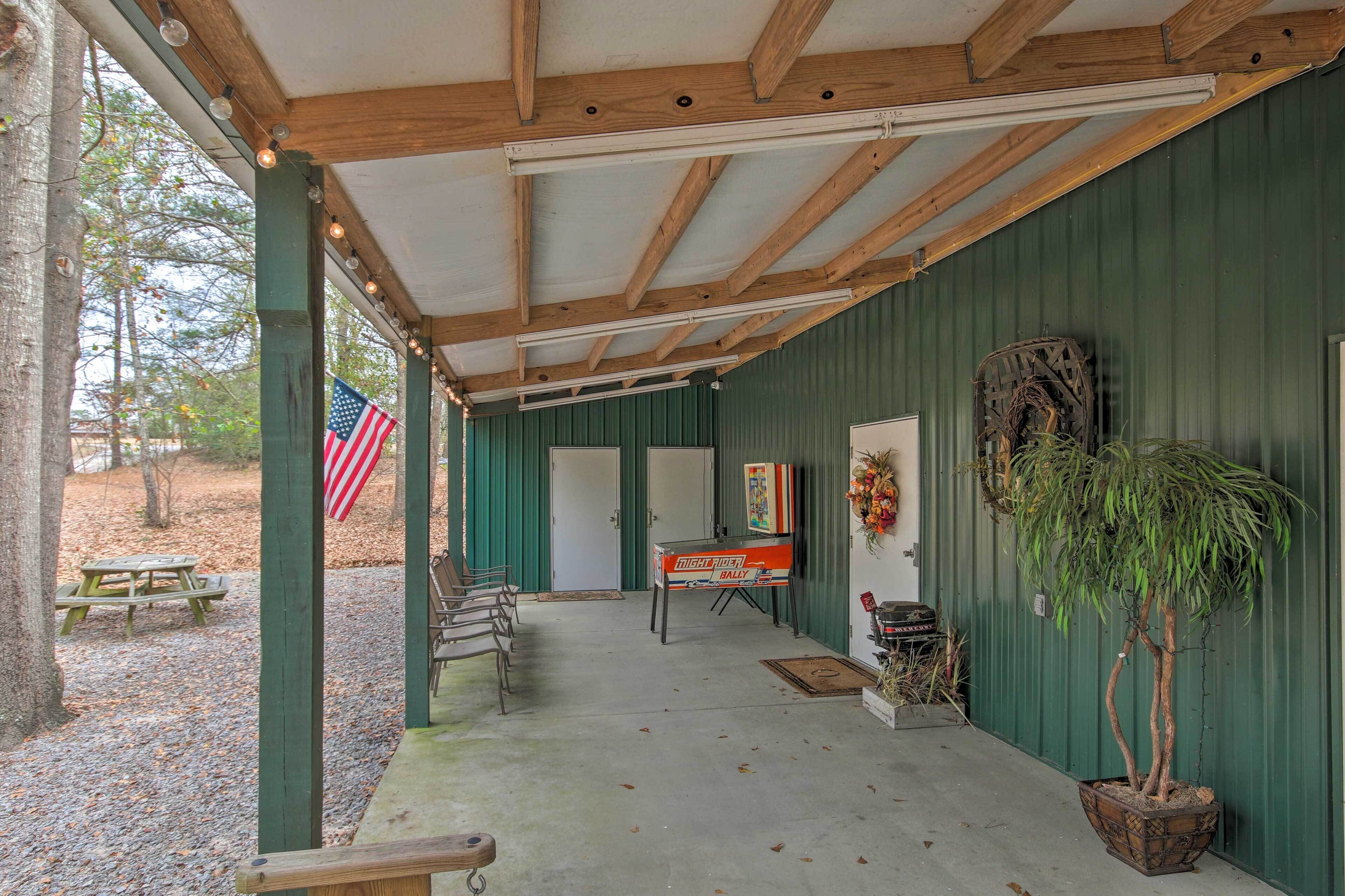 A covered porch with a picnic table, a dartboard, and a potted plant.