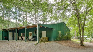 Ein rustikales Blockhaus mit überdachter Veranda, Holzmöbeln und einem Kranz an der Wand.