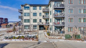 A multi-story residential building with balconies, a covered entrance, and a landscaped garden area. - Winter Park Condo w/ Balcony ~ 4 Mi to Slopes (Winter Park)