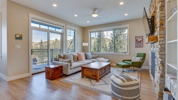 A spacious living room with a large window, a stone fireplace, and a cozy seating area. - Winter Park Condo w/ Balcony ~ 4 Mi to Slopes (Winter Park)