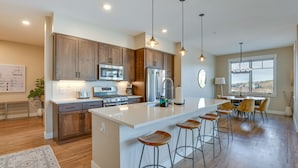 A modern kitchen with wooden cabinets, stainless steel appliances, and a central island with bar stools. - Winter Park Condo w/ Balcony ~ 4 Mi to Slopes (Winter Park)