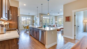 A spacious kitchen with a central island, wooden cabinets, stainless steel appliances, and pendant lighting. - Winter Park Condo w/ Balcony ~ 4 Mi to Slopes (Winter Park)