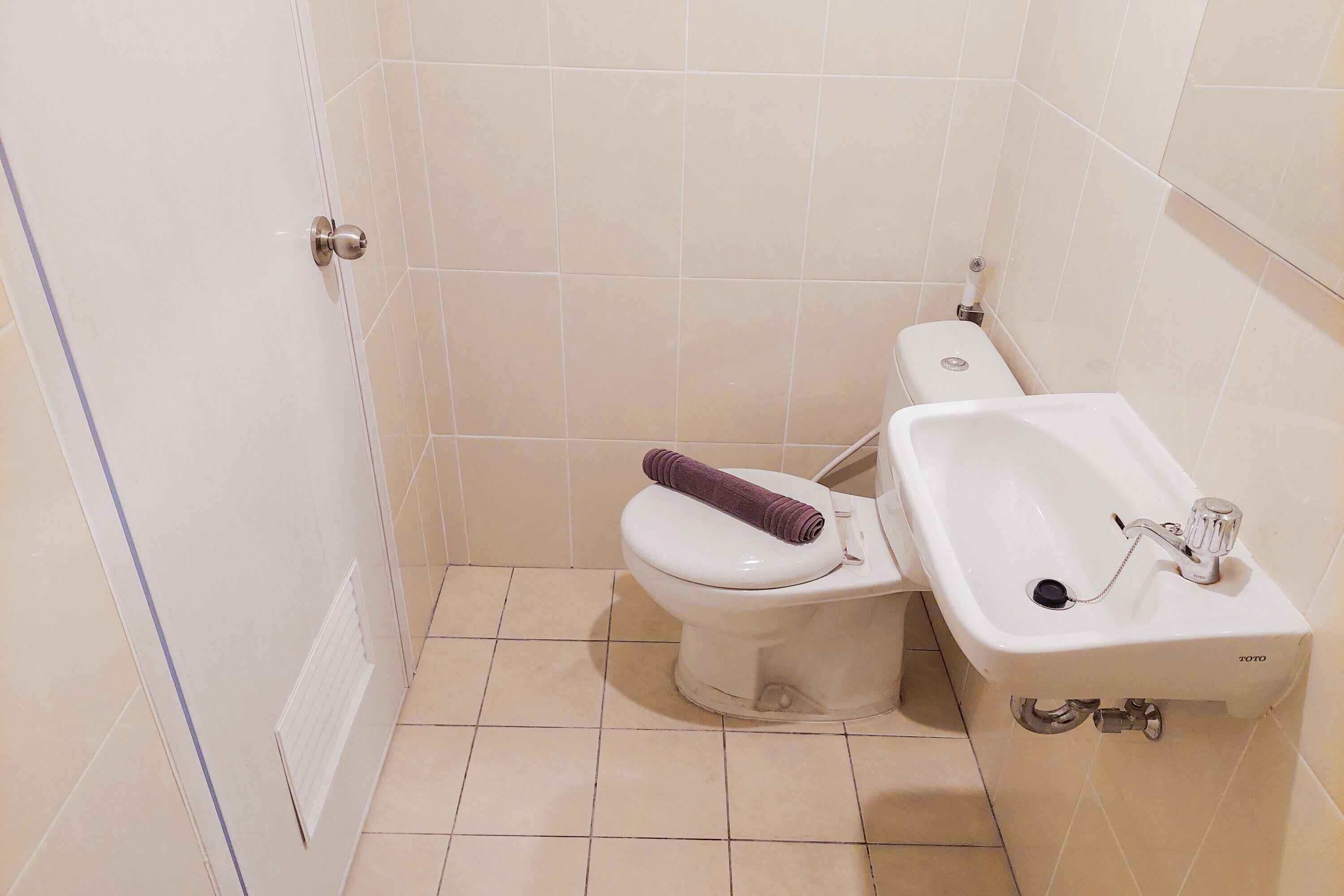 Un baño con inodoro, lavabo y suelo de baldosas.
