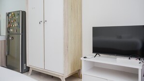 A kitchen with a refrigerator, a wooden cabinet, and a television on a stand. - Nice And Comfy Studio Apartment At M-Town Residence (Gading Serpong)