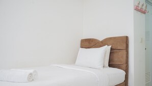 A neatly made bed with white linens and a brown headboard in a hotel room. - Nice And Comfy Studio Apartment At M-Town Residence (Gading Serpong)