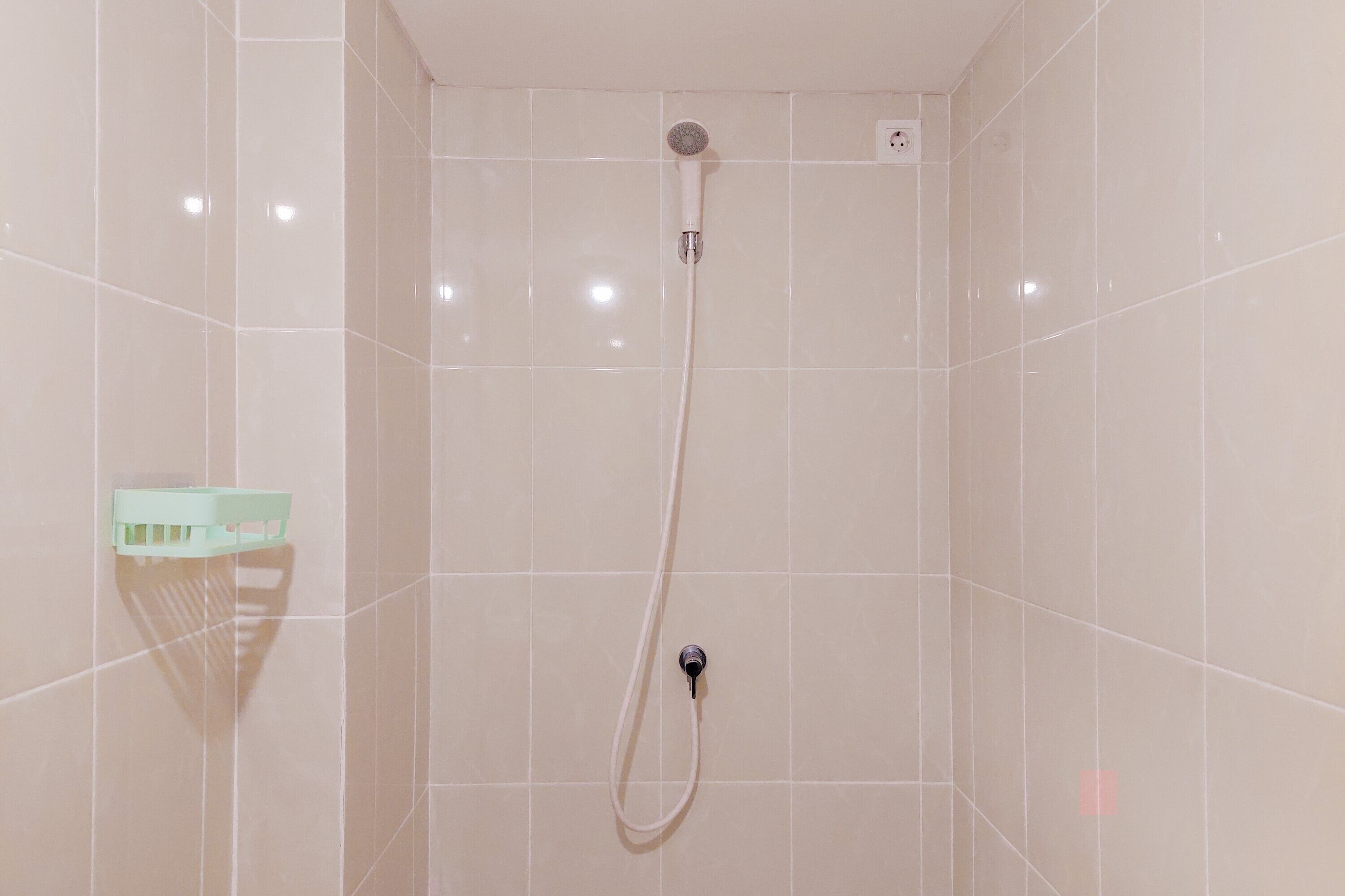 A shower with a handheld showerhead and a wall-mounted faucet.