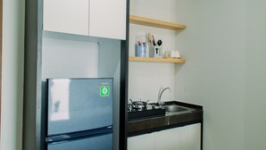 A compact kitchen with a stainless steel refrigerator, a sink, and wooden shelves above the countertop. - Elegant And Comfy 2Br Transpark Bintaro Apartment (South Tangerang)