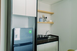 Eine kleine Küche mit einem Edelstahl-Kühlschrank, einem Spülbecken und Holzregalen über der Arbeitsplatte.