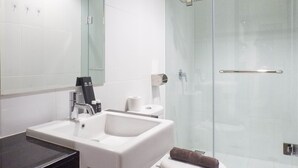 A modern bathroom with a white sink, mirror, and glass shower enclosure. - Exclusive 1Br At Apartment Praxis (Surabaya)